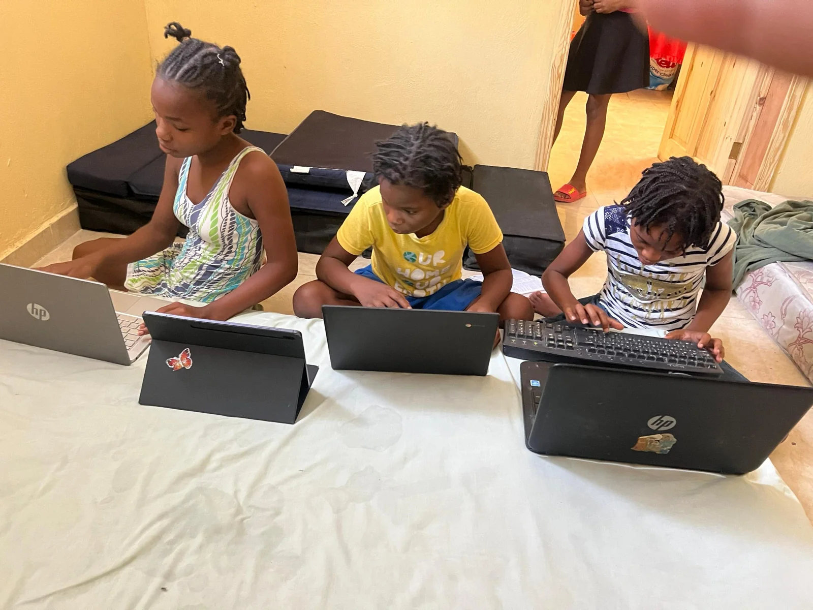 Three children working together at laptops during an INHO learning activity